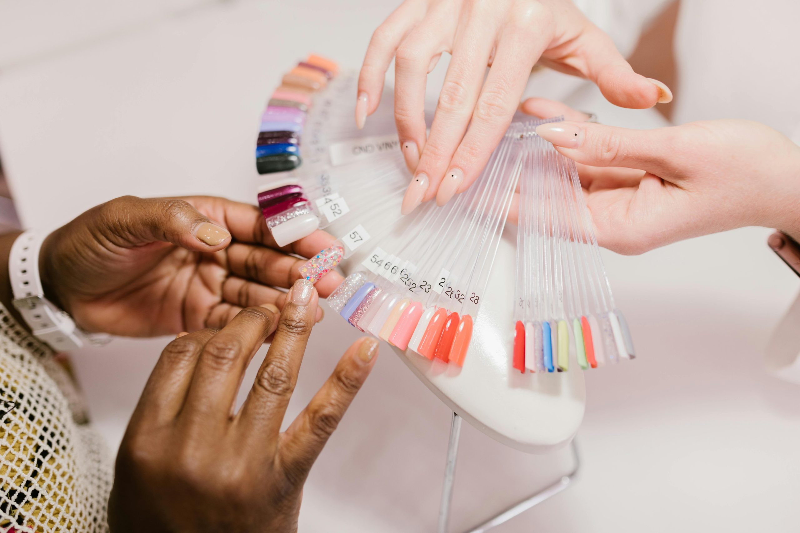 Close-up of hands choosing from a vibrant nail polish sample palette in a salon setting.