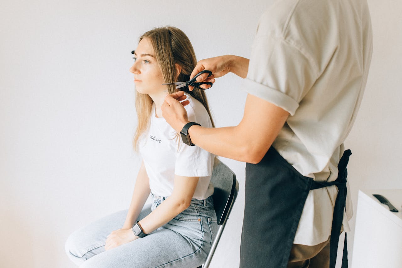 Woman in White Shirt and Blue Denim Jeans Getting a Haircut