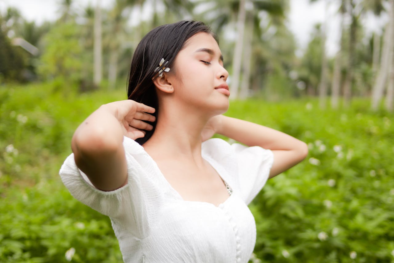 A woman in white embraces tranquility in a lush, green field scene.