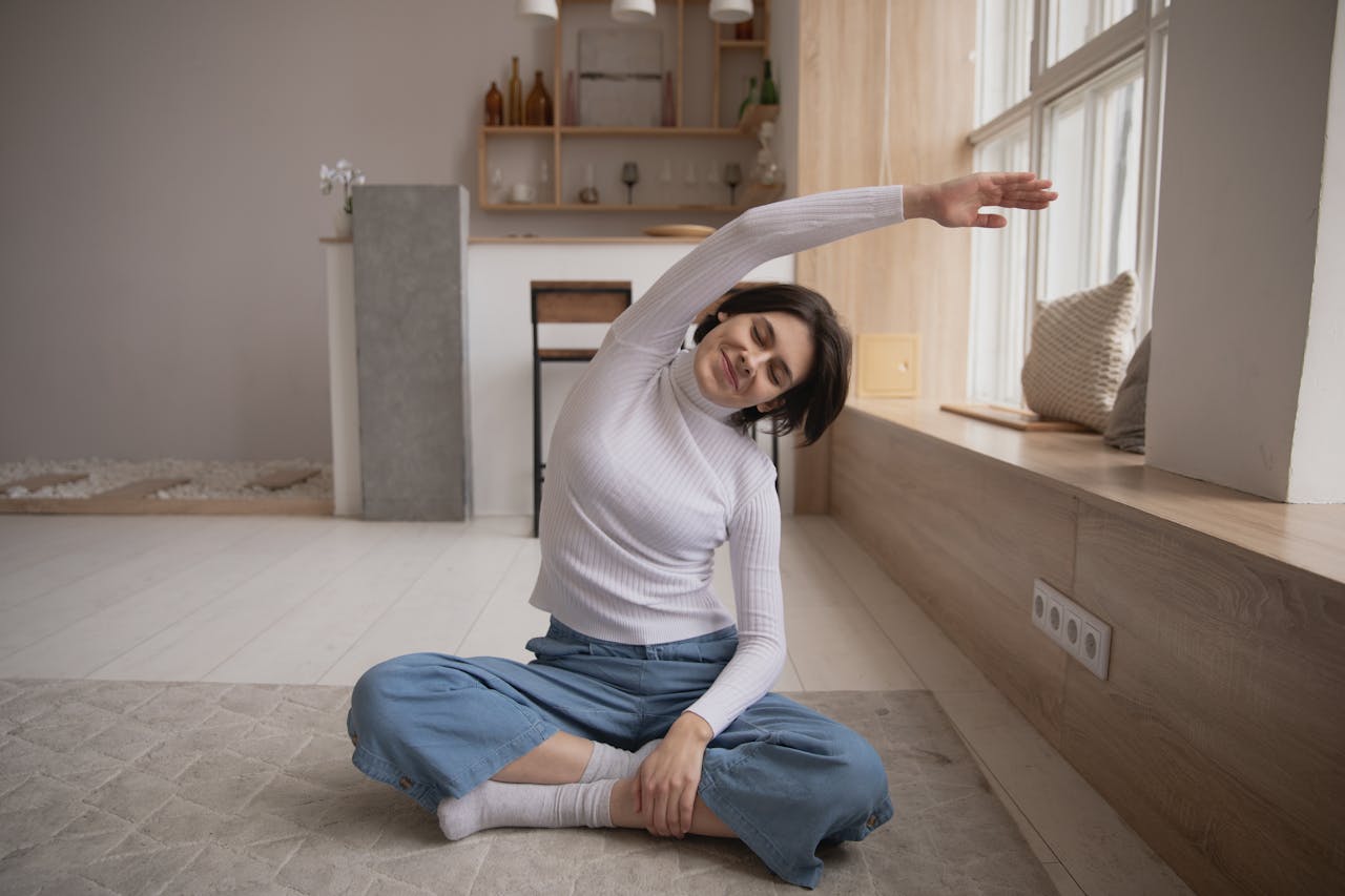 A young woman sitting in a peaceful home, stretching while practicing yoga for relaxation.