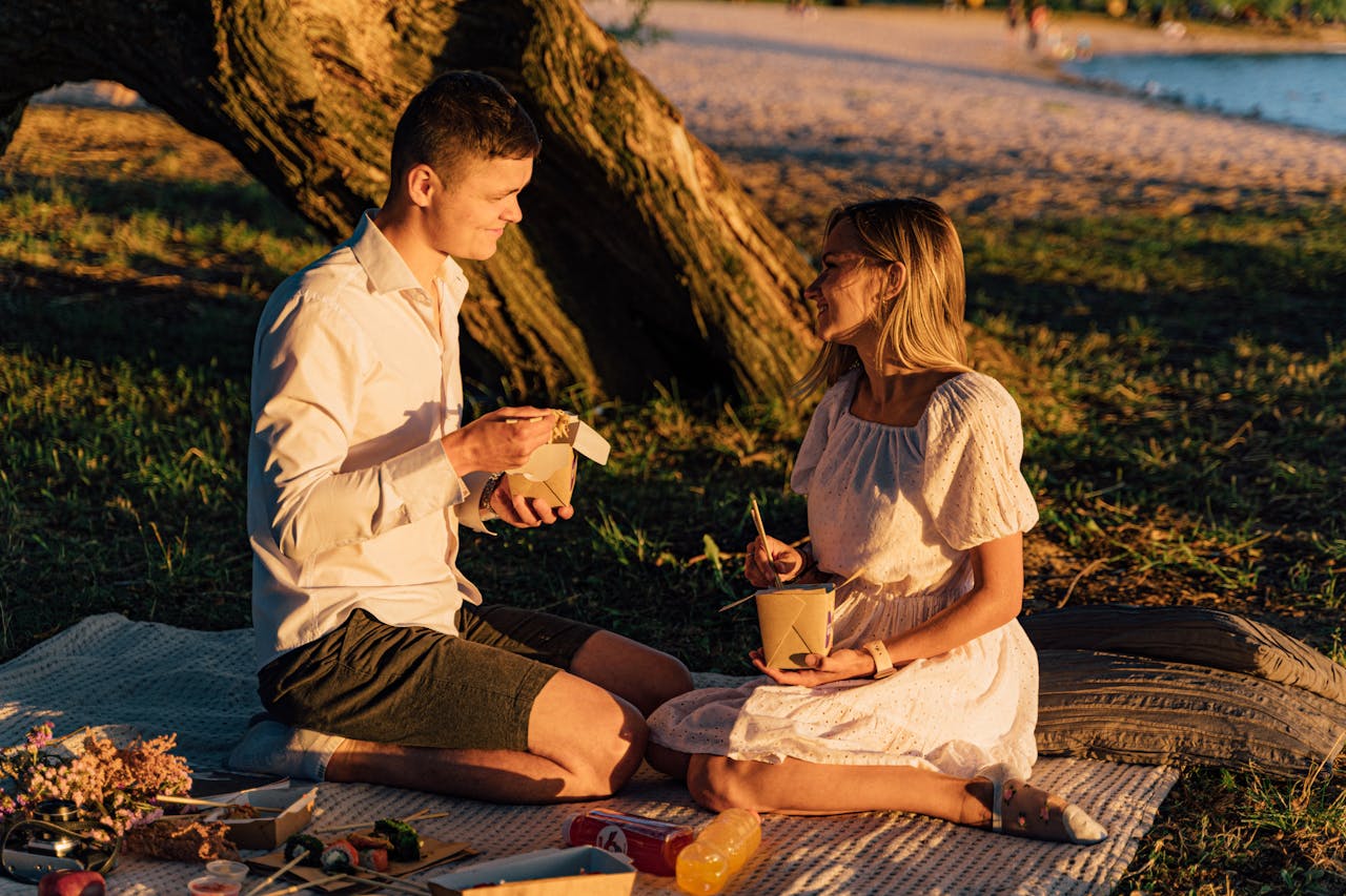 services-09 Couple enjoys a sunset picnic with takeout noodles by the beach. Perfect summer evening.