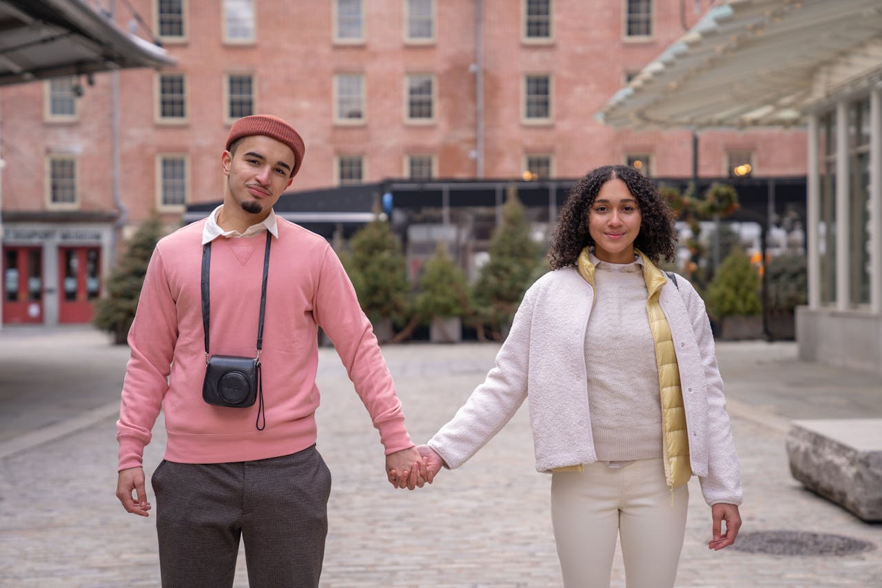 A happy couple holding hands, enjoying a day out in the city streets.