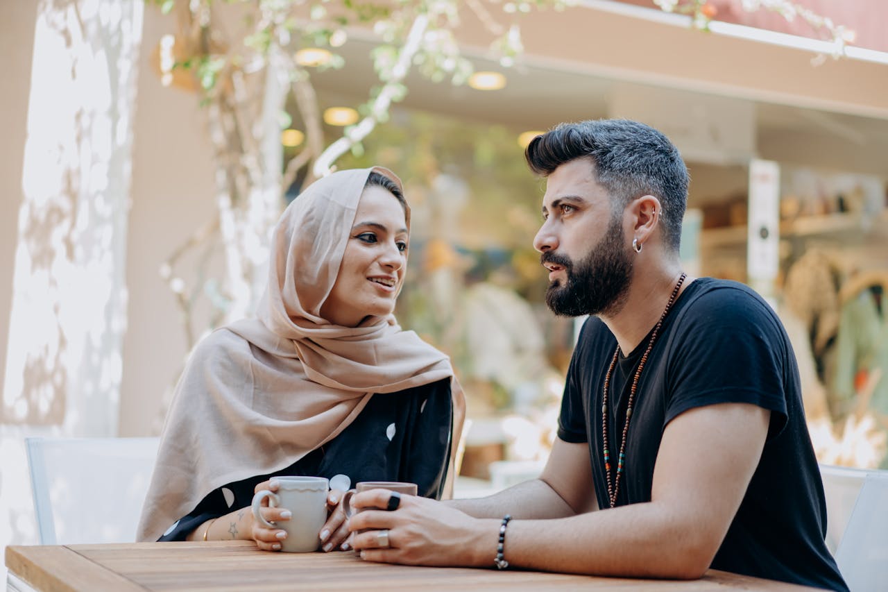 services-06 A Muslim couple shares a moment of affection while enjoying coffee outdoors.