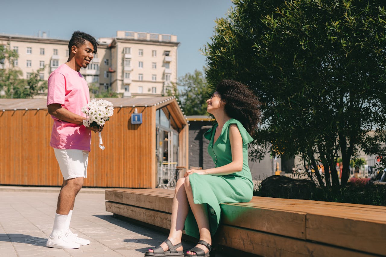 Man surprises woman with flowers in a romantic outdoor setting.